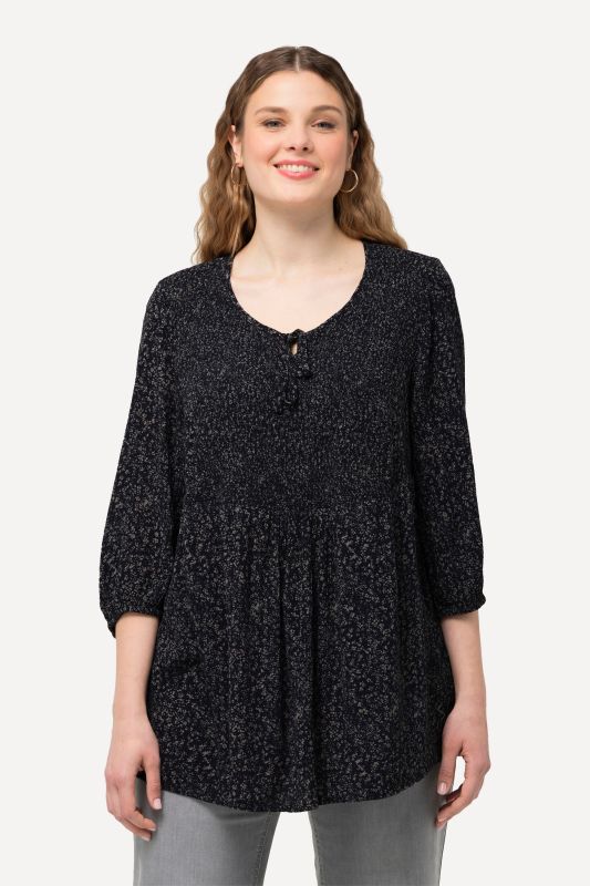 Blouse smockée à pois, avec décolleté rond et manches 3/4. Silhouette en A.