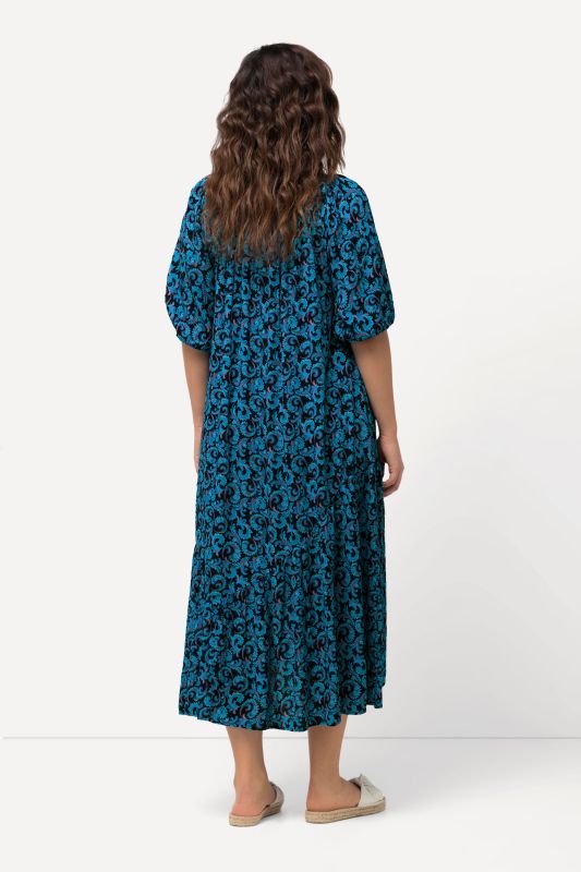 Robe midi à col rond et manches courtes. Volant à la base et motif vrilles