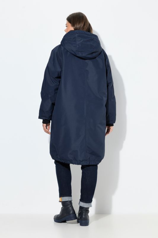 Veste technique oversize à capuche. Doublure polaire bouclée. Fermeture éclair à double sens
