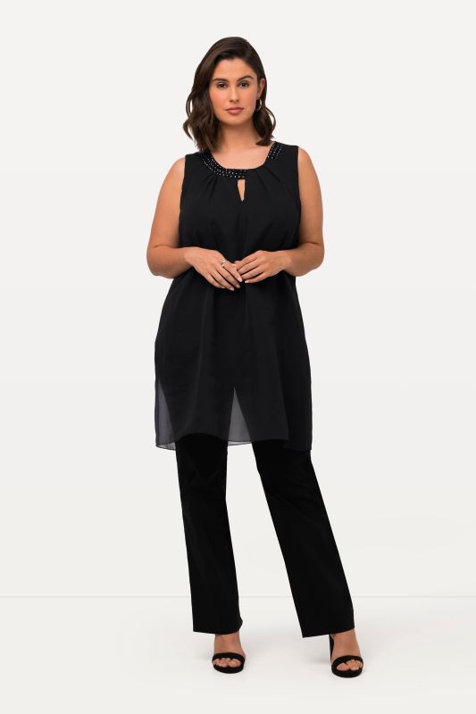 Tunique longue, sans manches. Coupe évasée. Décolleté rond à pierres fantaisie