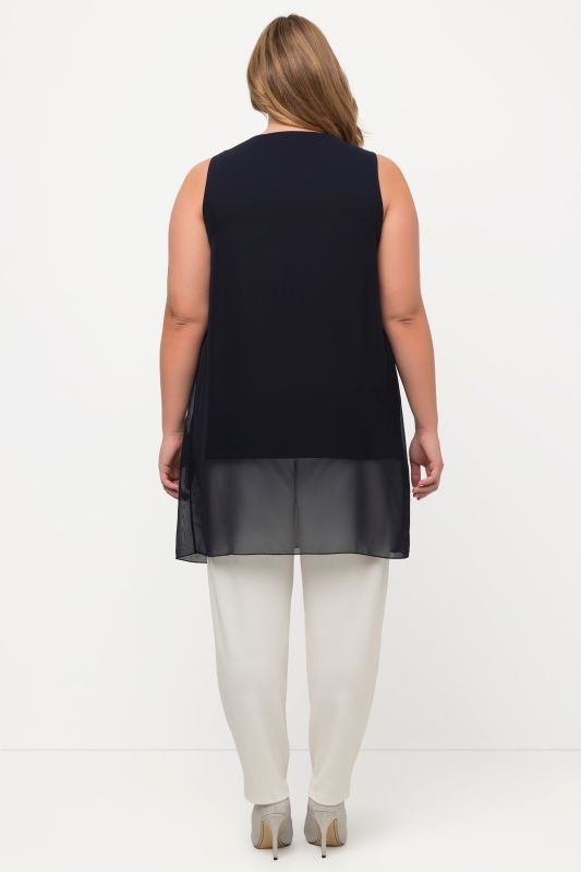 Tunique longue, sans manches. Coupe évasée. Décolleté rond à pierres fantaisie