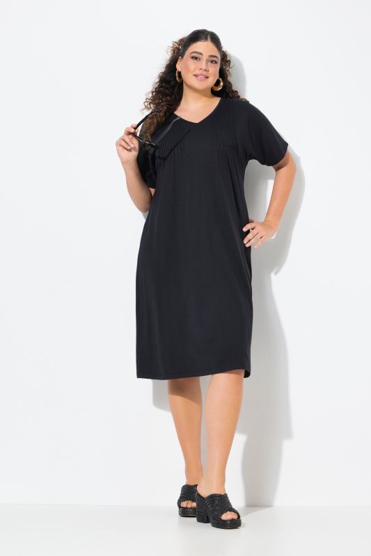 Robe en jersey à plis fantaisie. Col V et manches courtes. Coupe évasée