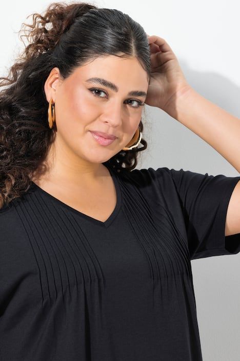 Robe en jersey à plis fantaisie. Col V et manches courtes. Coupe évasée