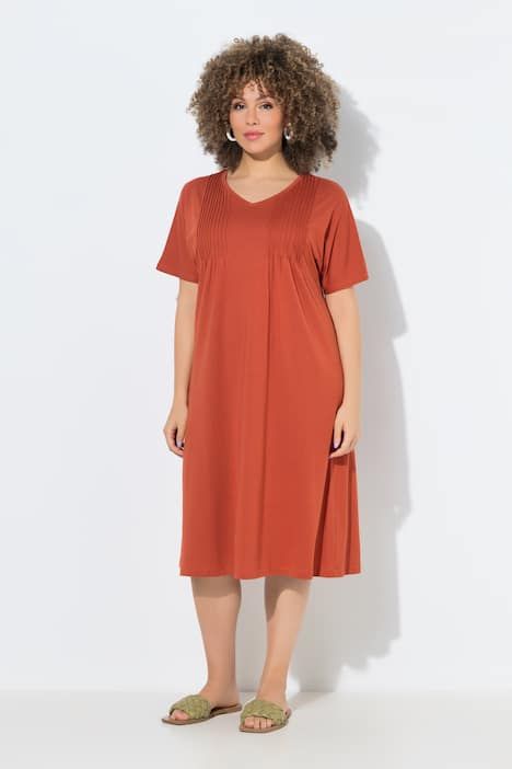 Robe en jersey à plis fantaisie. Col V et manches courtes. Coupe évasée